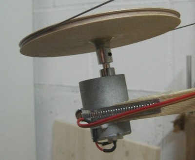 Die Umlaufrollen hat mein Vater aus Holz auf einer kleinen Drehbank gefertigt. Durchmesser 120 mm.<br />Zunächst hatte mein Modellbaumotor den mein Vater noch übrig hatte zuwenig Drehmoment für einen ruhigen Lauf.<br />Dann habe ich mir in China einen kleinen Motor bestellt mit 12 rpm bei 15V (Drehmoment war leider nicht angegeben aber der Hinweis 'großes Drehmoment') den ich mit einem Fischer-Technik-Trafo betreibe.<br />Jetzt hat die Bahn eine schöne Geschwindigkeit und läuft regelmäßig.