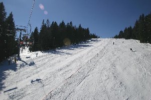 Die Bahn kreuzt die Piste und den Schlepper Jasa.