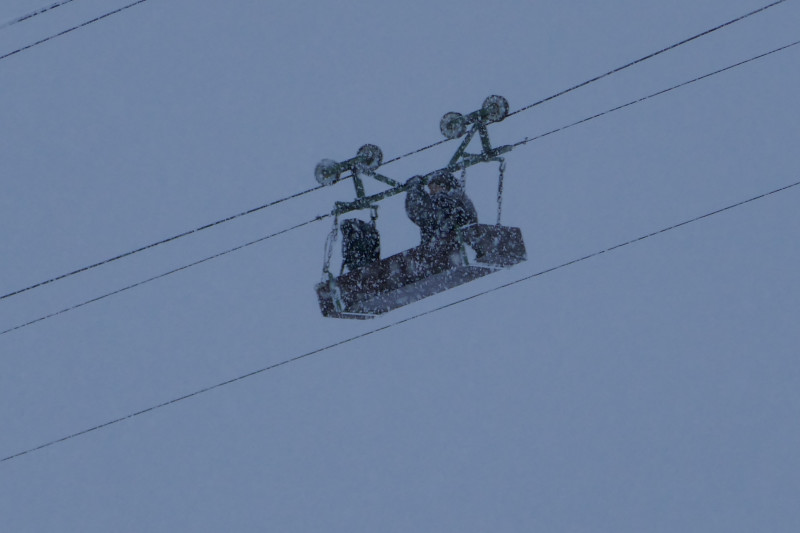 Mann an Bord. In der einsetzenden Dunkelheit und bei dem Schneefall war ich mir nicht sicher. Jetzt bin ich es: Da sitzt tatsächlich einer in der Materialseilbahn