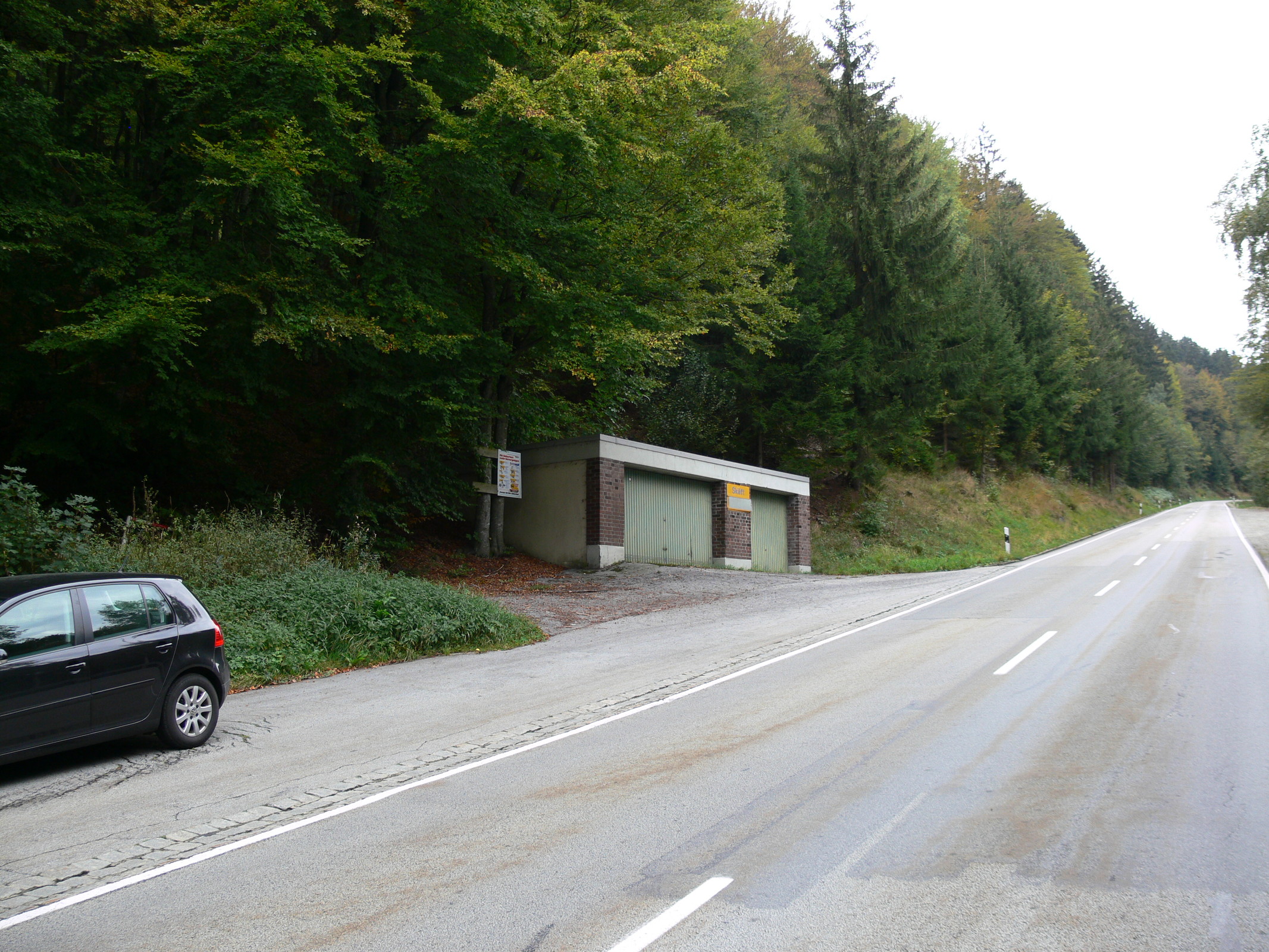 Nur diese Garage und ein paar Parkplätze an der Straße verraten, dass sich hier im Wald ein Schlepper versteckt.