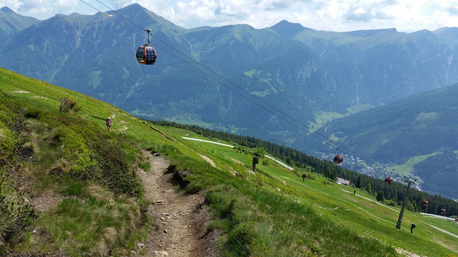 Wir schrauben uns nach oben. Es ist sehr heiß und die Sonne kann oberhalb der Baumgrenze volle Kraft ausüben. Kaum zu glauben, dass auf diesem unebenen, bewachsenen Gelände im Winter eine Abfahrt drübergeht. Aber hier bin ich selbst schon gefahren, und die Schneekanonen beweisen es auch. Echt schön!