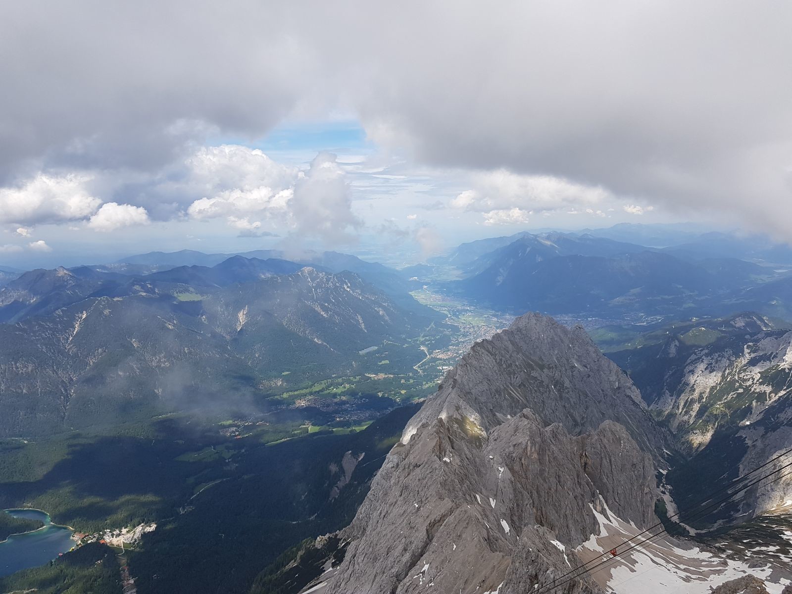 Oben am Gipfel hatten wir dann diese tolle Aussicht auf Garmisch-Partenkirchen und das Flachland (hinten), auf den Eibsee (links) und auf das Höllental (rechts) mit dem Massiv des Waxensteins (mittig).