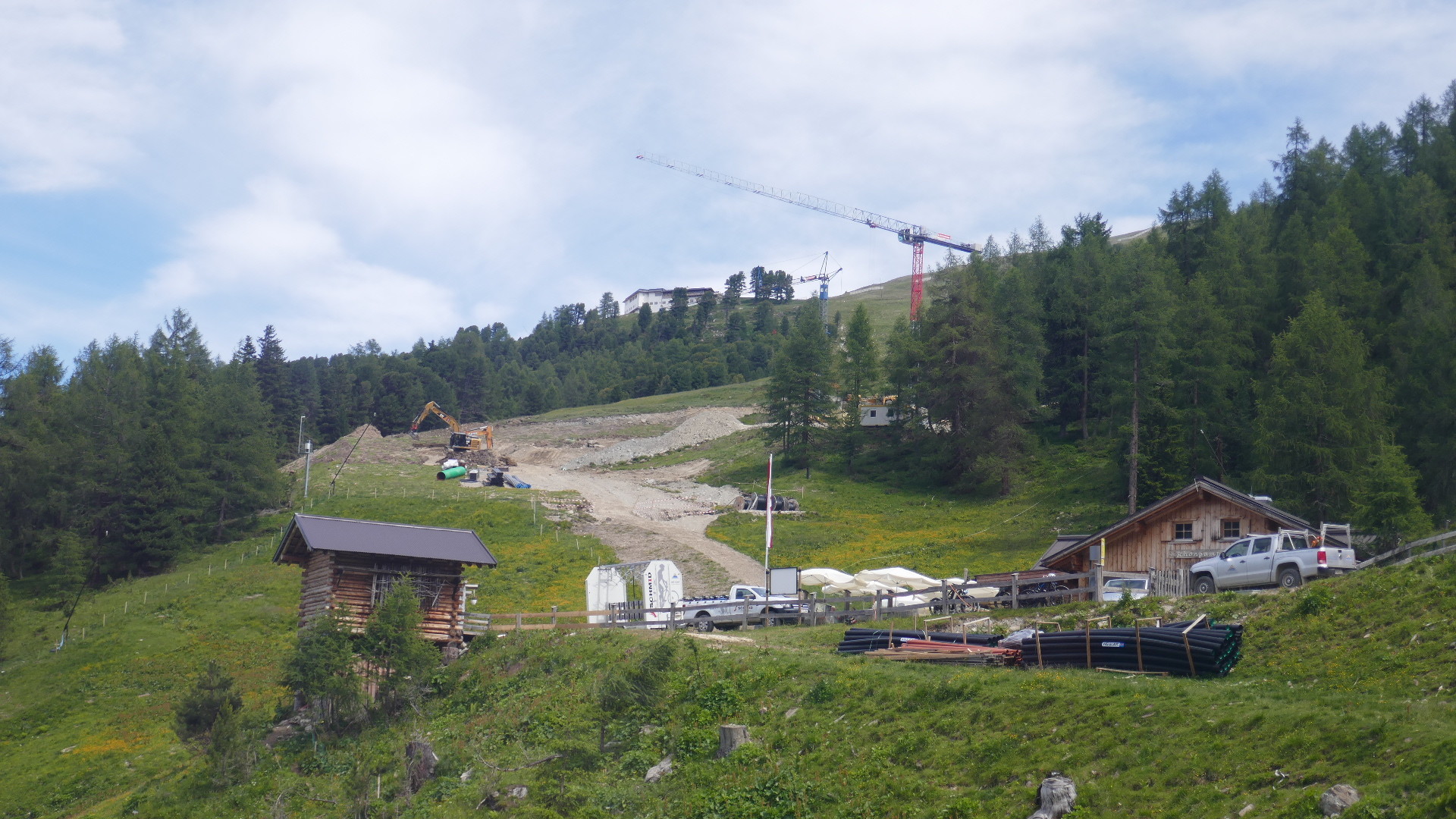 Von weiter unten. Die Talstation der neuen Bahn wird rechts hinter dem Wald bei den Kränen und dem Container liegen.
