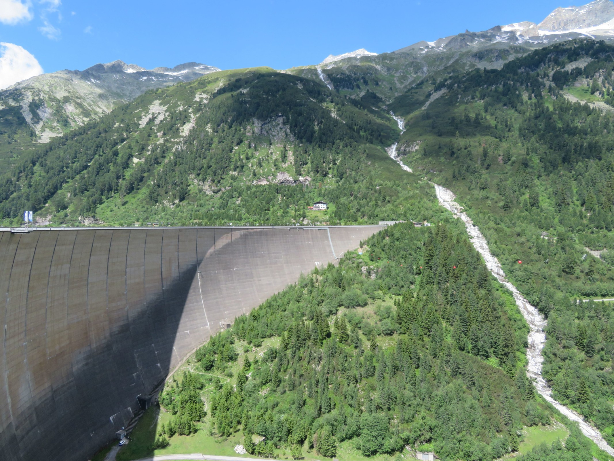 Die gewaltige Staumauer und rechts daneben der trockengelegte Bach.