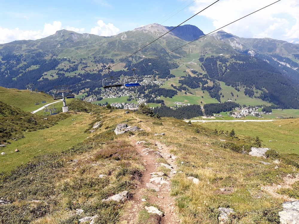 Zu Beginn ist der Weg schmal und mit scharfen Kanten versehen. Solche Wege mag ich nicht sonderlich. Andererseits ist es jeweils eine Herausforderung und Konzentrationsübung. Eine "Verkeilung" des Vorderrads mit dem dem steilen Wegrand ist unbedingt zu vermeiden, da ein Sturz sonst fast sicher wäre. Hier befinde ich mich übrigens ungefähr dort, wo im Winter die Talabfahrt nach Parpan abzweigt (Piste 25). Im Bild ist die 6KSB Weisshorn, die das erste Mal überhaupt Sommerbetrieb hat.
