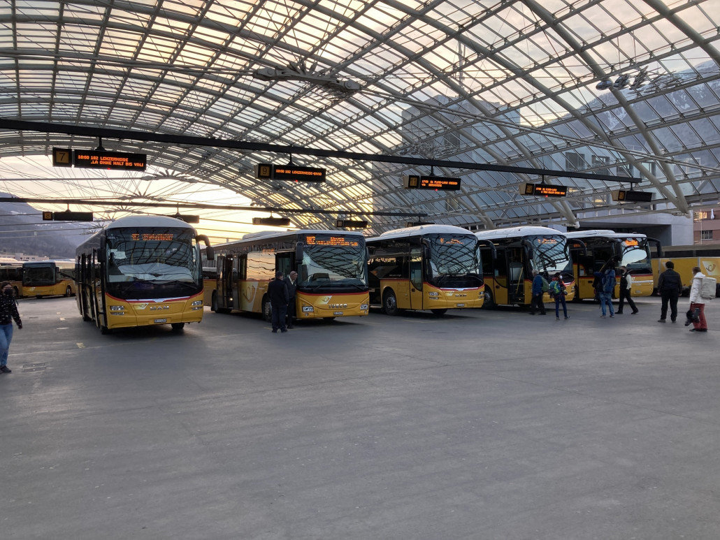Um kurz vor 18 Uhr erreichte ich Chur. Ab der Postautostation fahren jeweils um die volle und halbe Stunde Busse in verschiedene Richtungen. Die Regionen Flims und Lenzerheide werden durchgehend alle dreissig Minuten angefahren. Die Kurse Richtung Flims und Lenzerheide werden mittlerweile meistens doppelt geführt. Ein Bus fungiert dabei in der Regel als "Bummler"  und bedient alle Haltestellen, ein Fahrzeug fährt als "Sprinter" vor und hält deutlich später das erste Mal zum Ein- oder Aussteigen. <br />In der Zwischenzeit verkehren ab Chur viele so genannte "Low-Entry"-Fahrzeuge, wie der hier zu sehende Iveco Crossway LE (2.v.l.). Im Gegensatz zu vollwertigen Niederflurfahrzeugen haben diese Busse lediglich bei der ersten und zweiten Türe einen stufenlosen Einstieg. Nach der hinteren Türe steigt der Fussboden über Stufen steil an. Dadurch müssen die mechanischen Komponenten (Motor, Getriebe, Aufhängungen etc.) weniger platzsparend verbaut werden.<br />Ebenfalls sind auf dem Bild drei Busse des hochflurigen Modells MAN Lion's Regio zu sehen. Dieser Typ bildete für längere Zeit die Mehrheit der in Chur verkehrenden Postautos.