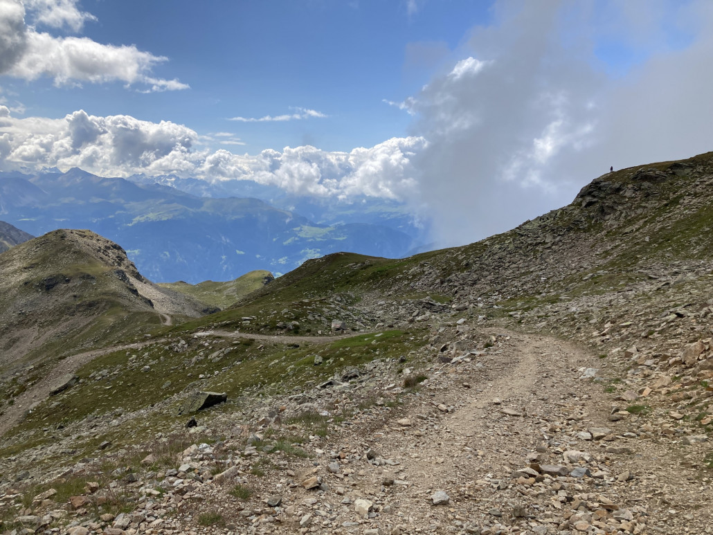 Von der Bergstation geht es zuerst auf einer breiten Schotterstrasse einige Kehren bergab. Es gäbe auch eine direkte, deutlich steilere und schmalere Variante. Da der Untergrund auf dieser aber noch loser ist, fahre ich jeweils den breiten Weg.