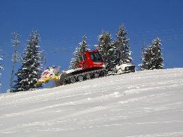 Ein Pistenbully schiebt Schnee zusammen