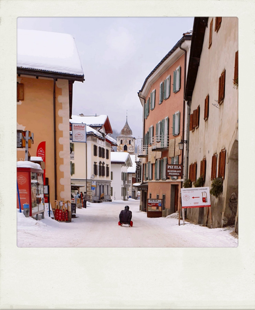 Die zweite Woche unseres Urlaubs ist schon in der Hälfte und wir waren noch nicht Schlitteln? Das muss heute an einem eher nicht so schönen Tag unbedingt nachgeholt werden. Schlittentest in der Hauptstraße, vor mir mein Vater.