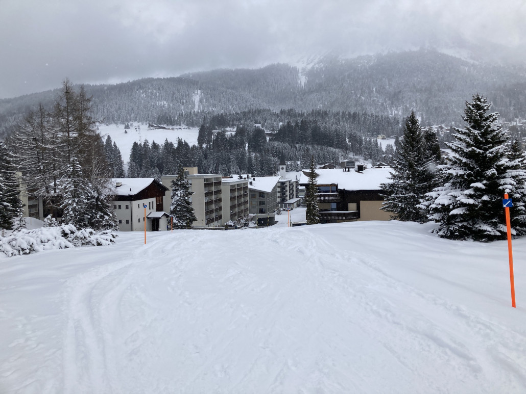 46. Ende der Talabfahrt im Dorf. Auch zu sehen eine "lenzerheidtypische" Überbauung in Form eines ziemlich massiven Wohnblocks. Häuser dieser Art gibt es einige im Dorf.