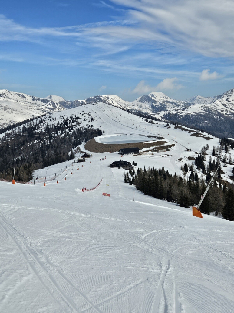 Mächtiger Speicherteich an der Bergstation der Nockalmbahn. Das "kleine" schwarze Gebäude davor ist die Bergstation der Gondelbahn. Links der Panoramalift. Rechts hinter dem Teich hinauf der Höhenlift.