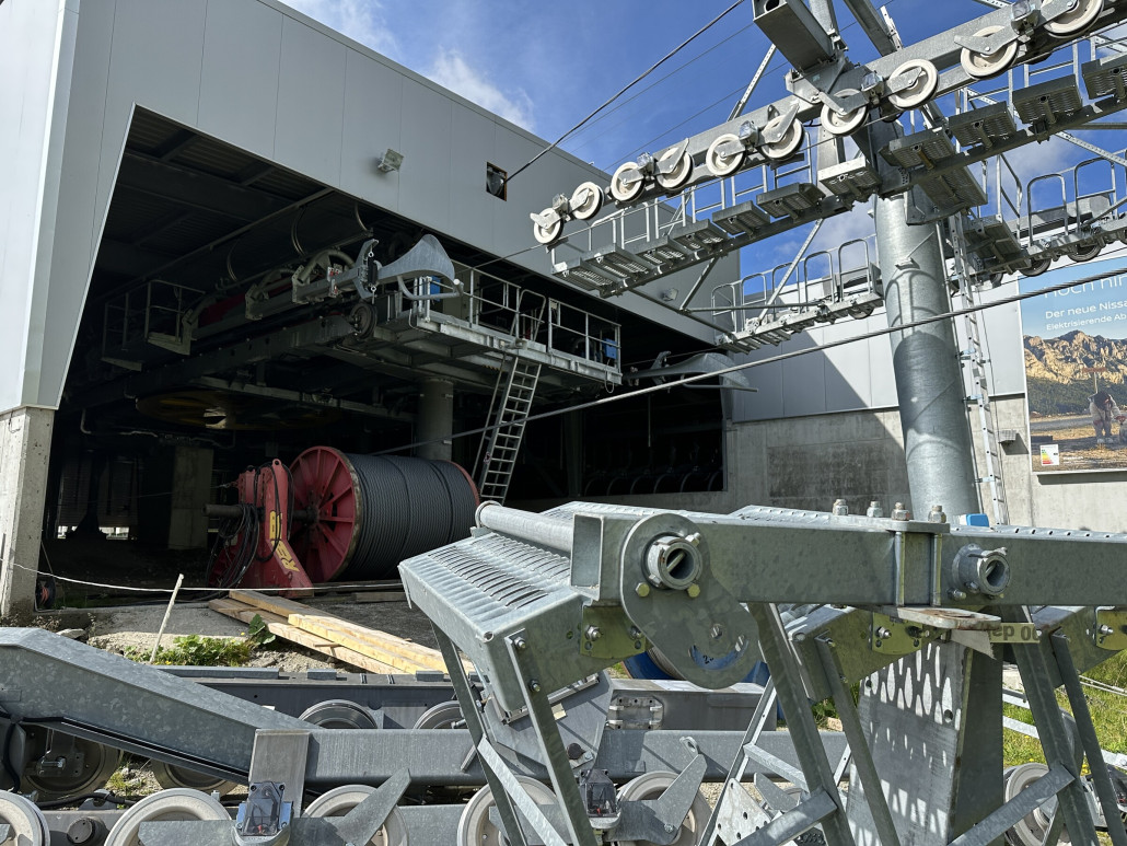 Talstation: hier ist das Förderseil teilweise auf eine Seiltrommel aufgerollt, ein Hilfsseil liegt auf den Stützen und der Seilscheibe. Um die Talstation liegen ehemalige Stützenteile.