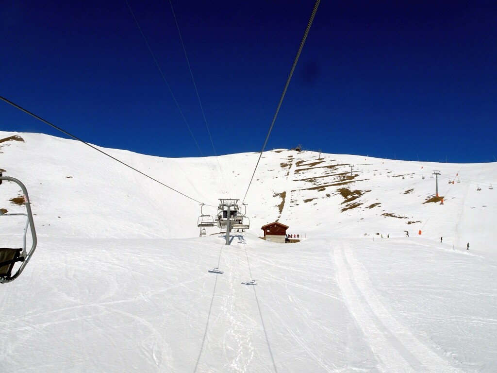Vor der Bergstation der 4er Sesselbahn Le Chiesso. Gut zu sehen die alte, steile  Trasse des Tellerliftes Corne.