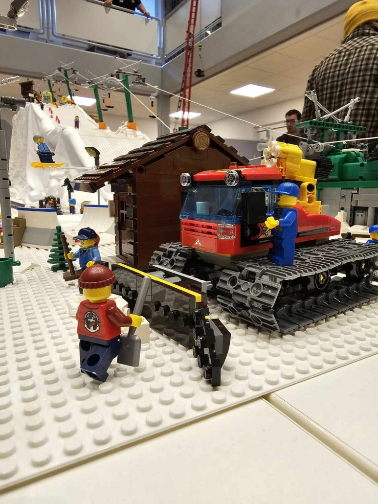 Pistenraupe mit Lift im Hintergrund.