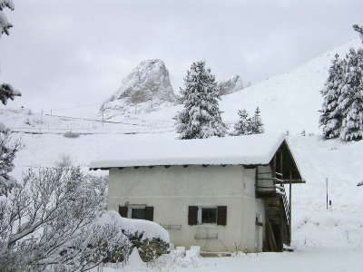 kleine, eingeschneite Hütte am Sellapass. Dahinter der Grohmannspitze und Teile der Fünffingerspitzen des Langkofelmassivs
