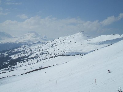 Blick von der High-Speed 4KSB Cumascheals auf die stark umgepflügte schwarze Piste. Die Auffällige Bergstation im Hintergrund ist der Piz Scalottas