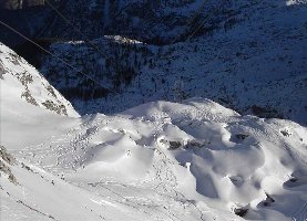 Blick aus der Seilbahnstation ins Tal, im Vordergrund freies Skigelände, an der sonnigen Stelle knapp am oberen Bildrand ist die von der Bergstation aus gesehen nächste Seilbahnstütze