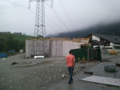 Von der Zufahrt aus gesehen sieht man den schrägen Tunnel zum unterirdischen Bahnhof, hinter der grünen PLane rechts neben dem Strommast