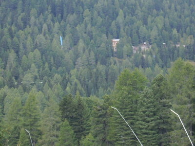 Mitten im Wald ein blauer Autokran, der ein Haus nach dem anderen aufstellt