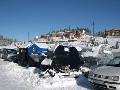6 neue Skikanonen am Parkplatz der Talstation, im Hintergrund Appartementneubauten